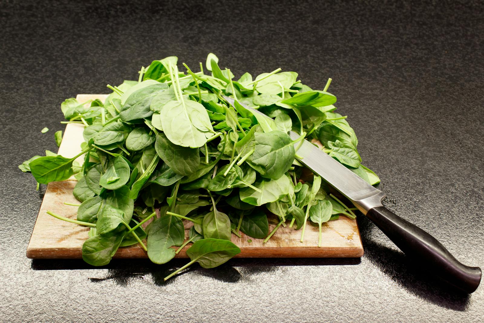 Fresh spinach on a wooden board — one of the best plant sources of iron, especially when paired with Vitamin C to boost absorption.