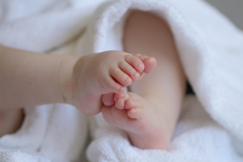 Close-up of newborn baby feet wrapped in a soft white towel — Fertility Panel blood test for reproductive health